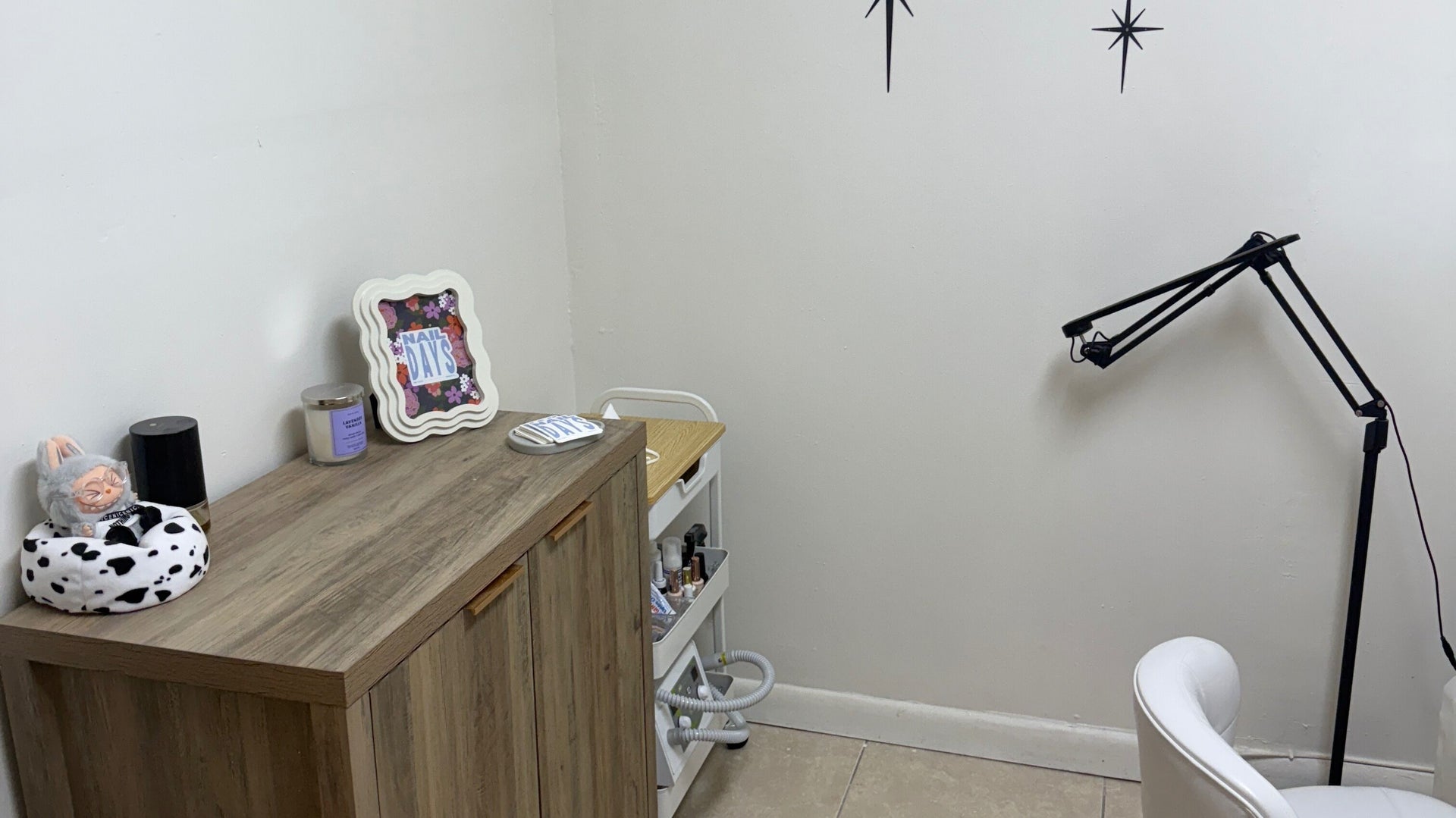 A corner of the studio with the framed Nail Days logo art, a candle and sparkle wall decals