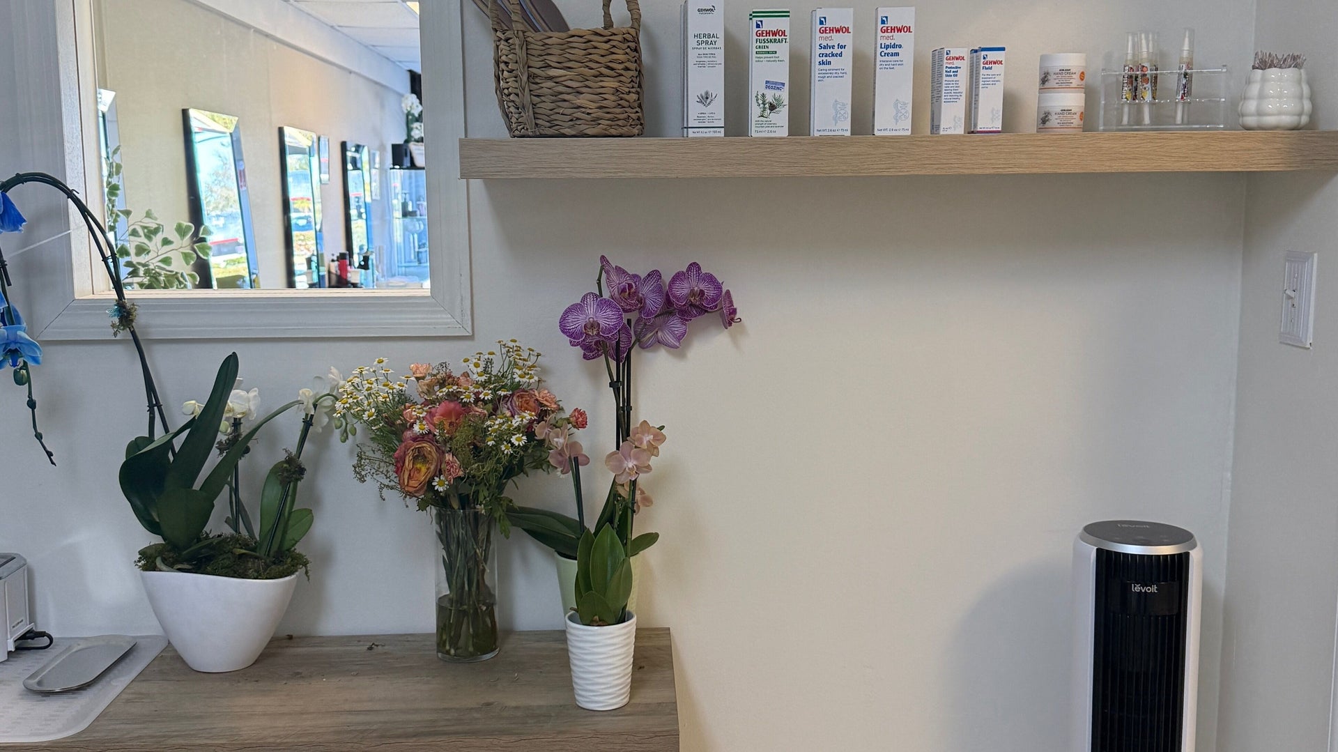 Care products, orchids and fresh flowers on the studio shelf